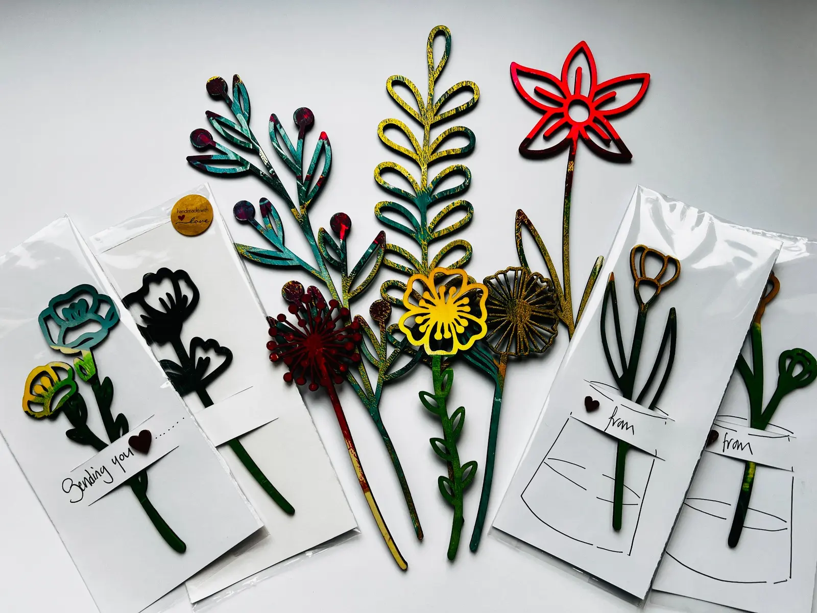 Colourful gelli printed wooden flowers arranged as handmade cards.